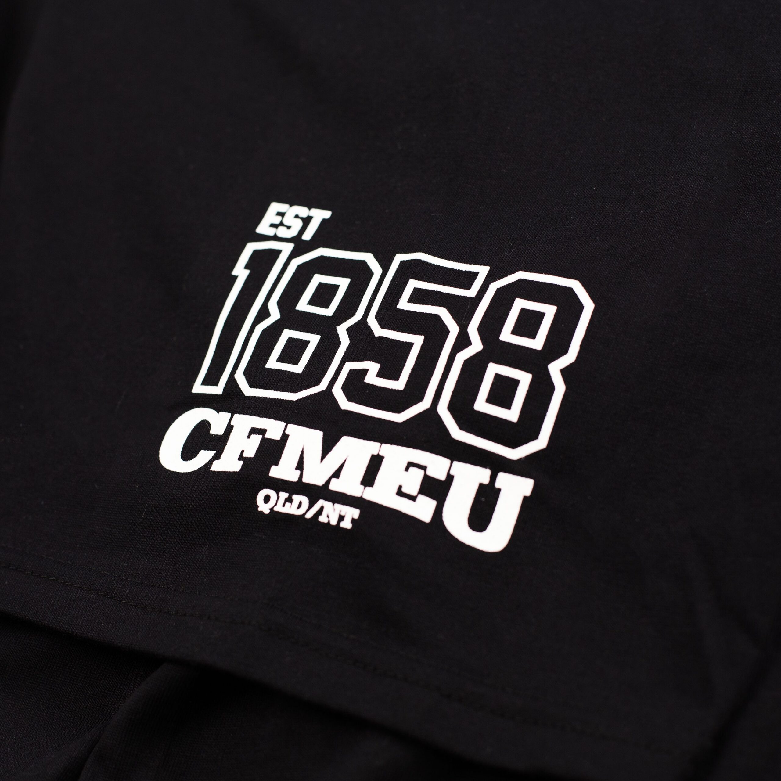 - CFMEU Queensland & NT Close-up of black fabric with a white outlined graphic reading 'EST 1900' on a garment.