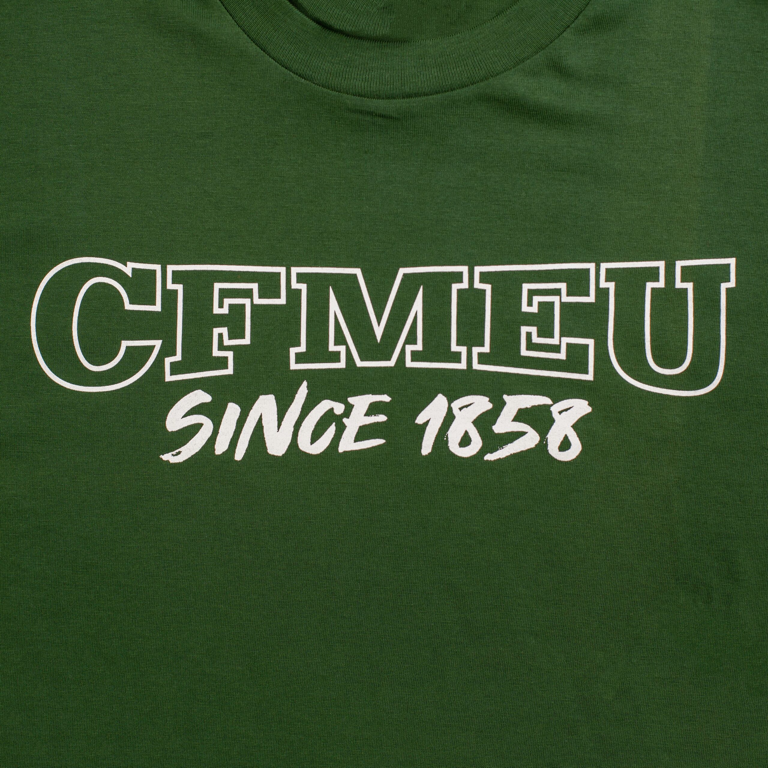 Green T-shirt with white outlined text reading 'GEMNET' and handwritten 'since 1956' beneath.