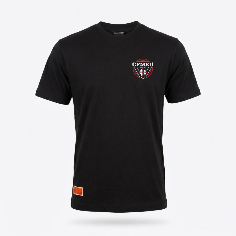 Black T-shirt featuring a small orange label patch near the bottom hem on the left side.