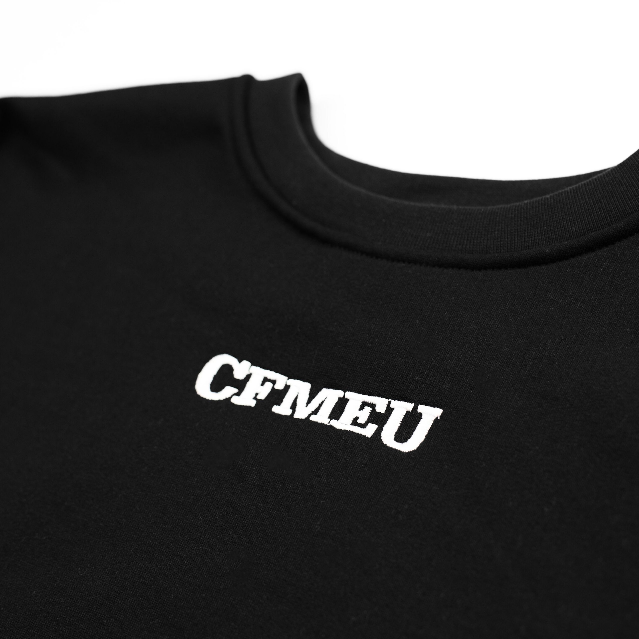 Close-up of a black T-shirt neckline with partial white text visible on the fabric.