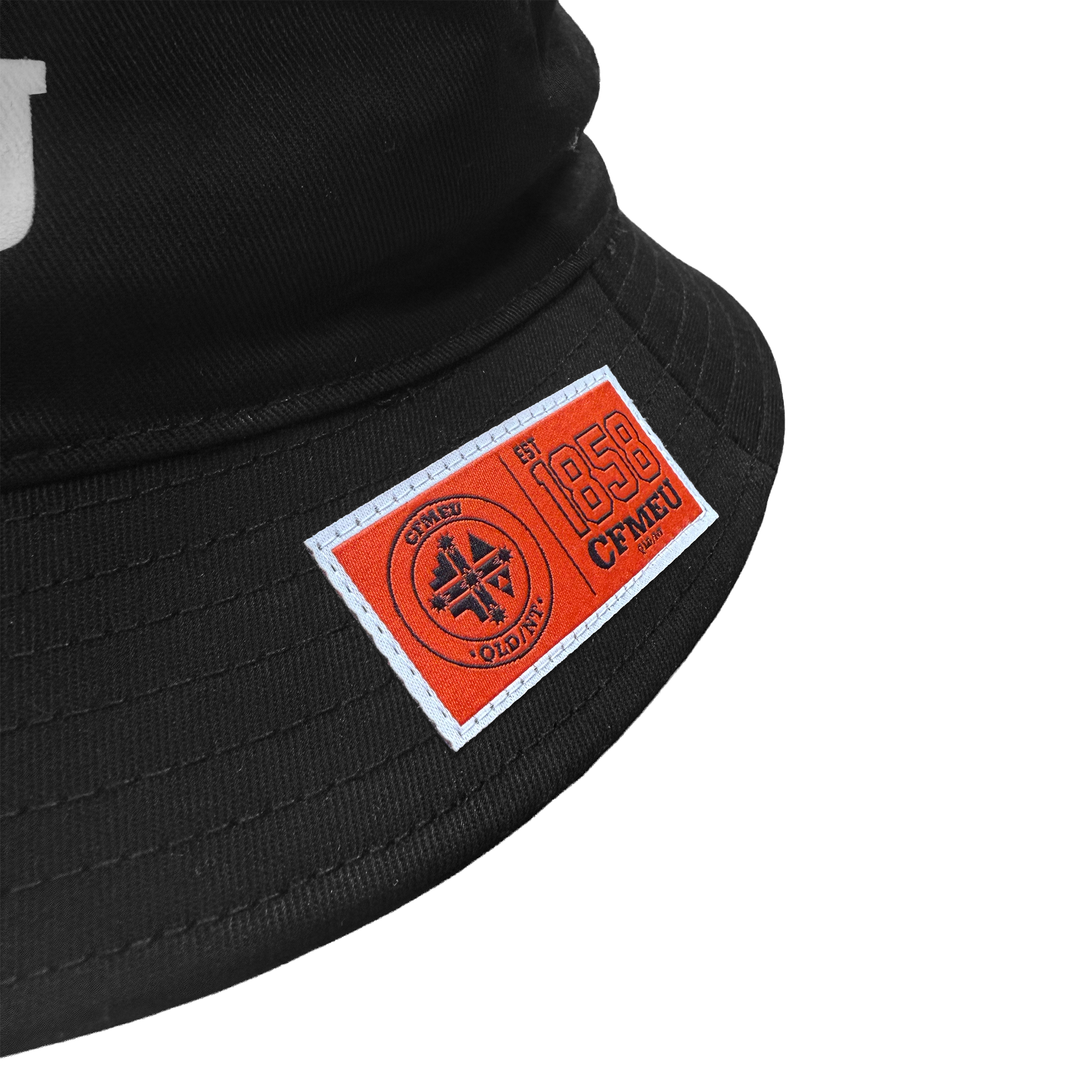 Close-up of a black cap brim with an orange rectangular patch stitched on the front edge, showing a circular emblem and text.
